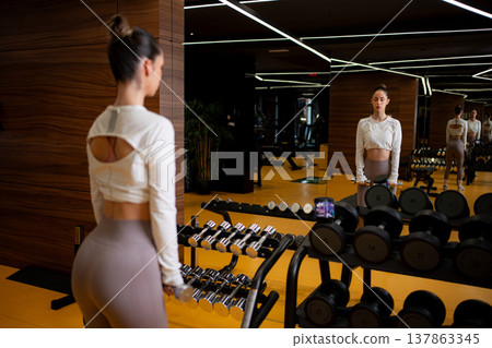 Woman exercising with dumbbells in modern gym Woman exercising with dumbbells in modern gym 137863345