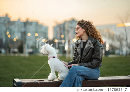 Young woman relaxing with cute dog in urban park Young woman relaxing with cute dog in urban park 137863347