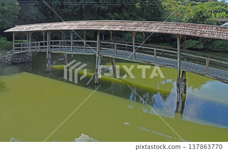 A traditional covered bridge in the Ishidatami district of Uchiko Town, Ehime Prefecture. The wooden structure is reflected in the water, creating a tranquil mountain village landscape. A traditional covered bridge in the Ishidatami district of Uchiko Town, Ehime Prefecture. The wooden structure is reflected in the water, creating a tranquil mountain village landscape. 137863770