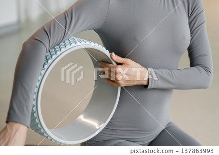 Person practices yoga with a wheel in a studio during a morning session for flexibility and balance improvement Person practices yoga with a wheel in a studio during a morning session for flexibility and balance improvement 137863993