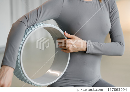 Person practices yoga with a wheel in a studio during a morning session for flexibility and balance improvement Person practices yoga with a wheel in a studio during a morning session for flexibility and balance improvement 137863994
