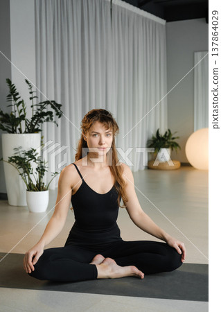 Woman practices yoga in a quiet studio with plants and soft lighting during a morning session focusing on mindfulness and relaxation Woman practices yoga in a quiet studio with plants and soft lighting during a morning session focusing on mindfulness and relaxation 137864029