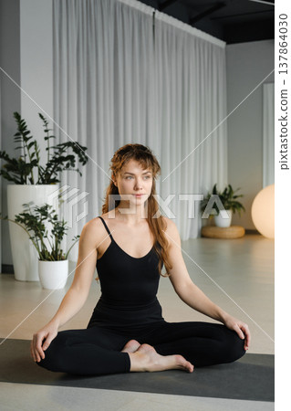 Woman practices yoga in a quiet studio with plants and soft lighting during a morning session focusing on mindfulness and relaxation Woman practices yoga in a quiet studio with plants and soft lighting during a morning session focusing on mindfulness and relaxation 137864030