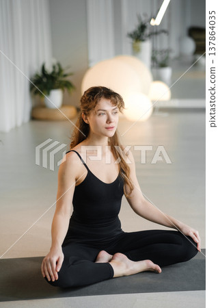 Woman practices yoga in a quiet studio with plants and soft lighting during a morning session focusing on mindfulness and relaxation Woman practices yoga in a quiet studio with plants and soft lighting during a morning session focusing on mindfulness and relaxation 137864035