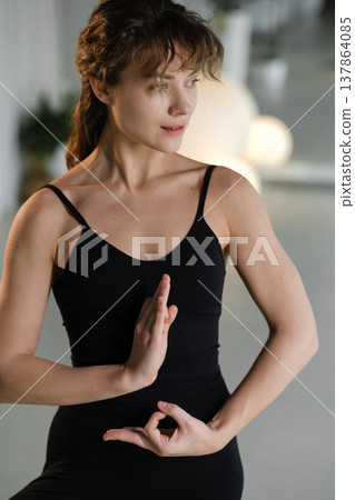 Woman practicing yoga poses indoors during a morning session in a bright studio 137864085
