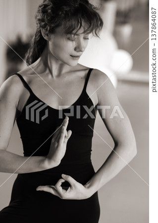 Woman practices yoga in a studio with plants and soft lighting during the day 137864087