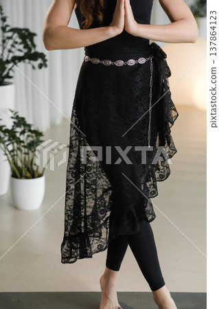 Woman stands in dance pose wearing black lace skirt and leggings in a bright indoor space with plants around Woman stands in dance pose wearing black lace skirt and leggings in a bright indoor space with plants around 137864123