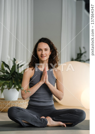 Woman practices yoga in a studio with plants and round lights during a morning session focused on mindfulness and relaxation Woman practices yoga in a studio with plants and round lights during a morning session focused on mindfulness and relaxation 137864347