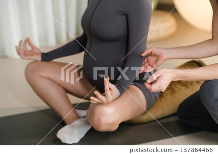 Meditation session in a wellness center with a pregnant woman and an instructor guiding her on breathing techniques and body awareness Meditation session in a wellness center with a pregnant woman and an instructor guiding her on breathing techniques and body awareness 137864466