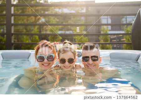 Family enjoys time in hot tub during sunny afternoon at home Family enjoys time in hot tub during sunny afternoon at home 137864562