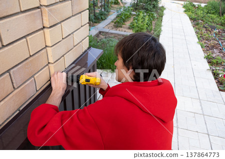 Worker installing house plinth with metal sheets during construction works 137864773