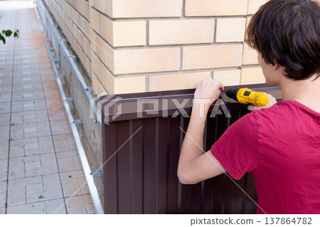 Worker installing house plinth with metal sheets during construction works 137864782