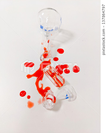 A broken ampoule and spilled liquid create a striking visual of fragility and potential danger 137864797