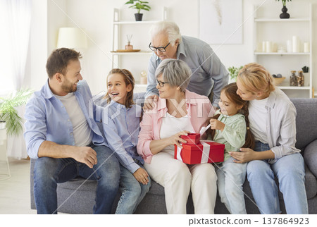 Three generations family portrait, congratulating hugging beloved senior grandma, close embracing Three generations family portrait, congratulating hugging beloved senior grandma, close embracing 137864923
