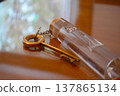A hotel table with a classic brass key and a clear acrylic keychain. 137865134