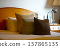 A hotel bedroom with a calm atmosphere, featuring warm-colored cushions. 137865135