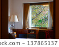 A classic hotel room with a view of trees changing color in autumn. 137865137