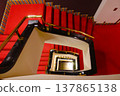 A classic hotel staircase with a red carpet and brass railings spiraling upwards. 137865138