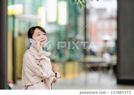 一位年輕的女商人正在街頭用手機打電話。 137865373