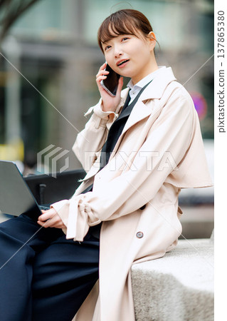 一位年輕的女商人正在街頭用手機打電話。 一位年輕的女商人正在街頭用手機打電話。 137865380
