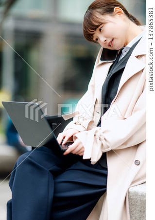 一位年輕的女商人正在街頭用手機打電話。 一位年輕的女商人正在街頭用手機打電話。 137865381