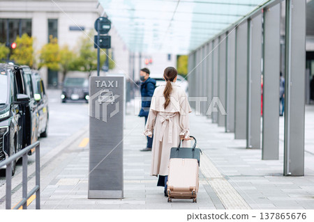 一位年輕的女商人正在城市裡等計程車。 一位年輕的女商人正在城市裡等計程車。 137865676