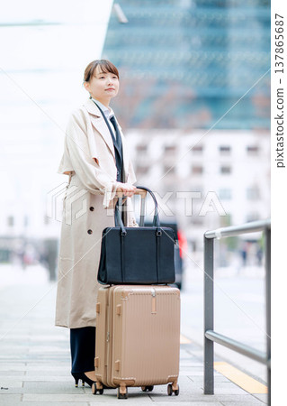 一位年輕的女商人正在城市裡等計程車。 137865687