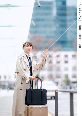 一位年輕的女商人正在城市裡等計程車。 一位年輕的女商人正在城市裡等計程車。 137865689