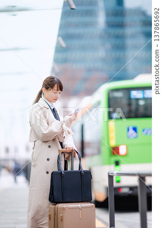 一位年輕的女商人正在城市裡等計程車。 一位年輕的女商人正在城市裡等計程車。 137865692