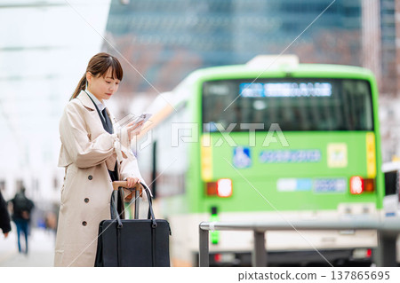 一位年輕的女商人正在城市裡等計程車。 一位年輕的女商人正在城市裡等計程車。 137865695