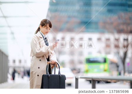 一位年輕的女商人正在城市裡等計程車。 137865696