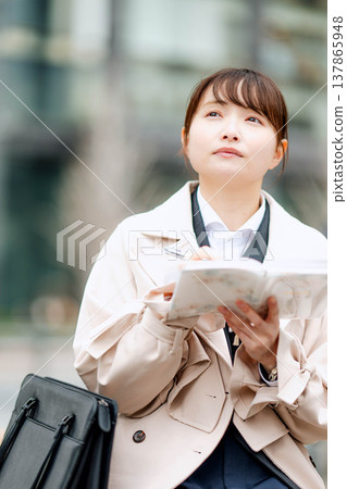 一位年輕的女商人正在查看她的日程表。 一位年輕的女商人正在查看她的日程表。 137865948