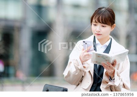 一位年輕的女商人正在查看她的日程表。 137865956
