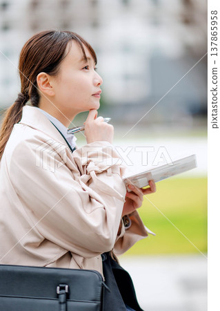 一位年輕的女商人正在查看她的日程表。 一位年輕的女商人正在查看她的日程表。 137865958