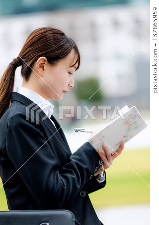一位年輕的女商人正在查看她的日程表。 137865959