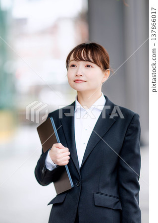 A young woman in a suit holding a laptop in one hand. A young woman in a suit holding a laptop in one hand. 137866017