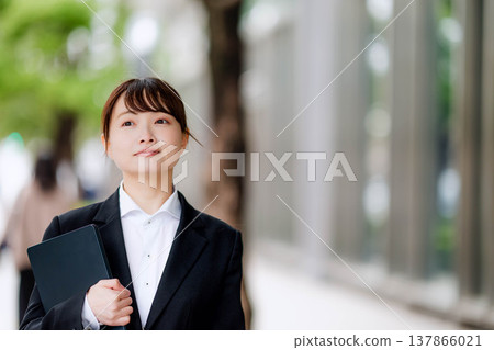 一位身穿西裝的年輕女子，一手拿著筆記型電腦。 137866021