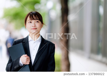 一位身穿西裝的年輕女子，一手拿著筆記型電腦。 137866022