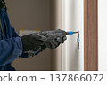 An electrician installing an electrical outlet at a renovation site, using a power drill to tighten the screws. 137866072