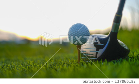 Golf clubs and balls on a green lawn in a beautiful golf course with morning sunshine. Golf clubs and balls on a green lawn in a beautiful golf course with morning sunshine. 137866182