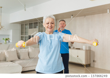Fitness workout training. Senior woman picking up dumbbells. Old adult mature healthy lady doing sports exercise at home. Grandmother have workout rehabilitation. Health care healthy lifestyle Fitness workout training. Senior woman picking up dumbbells. Old adult mature healthy lady doing sports exercise at home. Grandmother have workout rehabilitation. Health care healthy lifestyle 137866249