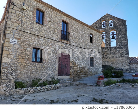 Rustic stone house and old church bell tower in Castellet village, Spain. 137866300