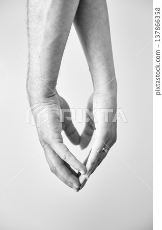 Close up of man's and woman's hands making heart symbol by hands. Couple holding hands on white background. Concept of love, intimacy, support, and trust. Black and white image. Close up of man's and woman's hands making heart symbol by hands. Couple holding hands on white background. Concept of love, intimacy, support, and trust. Black and white image. 137866358