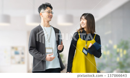 Two businessmen, a man and a woman, talking while walking through the office 137866643