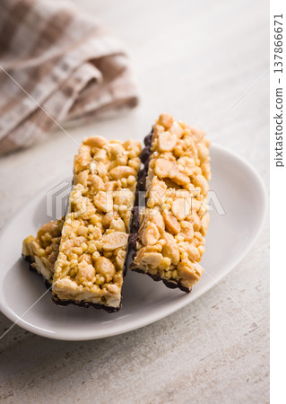 Stacked Peanut Granola Bars With Chocolate Coating On Plate, Crunchy Snack Food Stacked Peanut Granola Bars With Chocolate Coating On Plate, Crunchy Snack Food 137866671