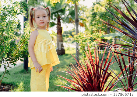 Happy cute girl in yellow dress enjoying summer in sunny park 137866712