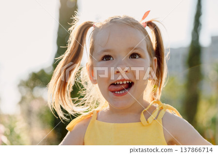 Happy girl smiling in warm sunlight outdoors, joyful childhood moment. Happy girl smiling in warm sunlight outdoors, joyful childhood moment. 137866714