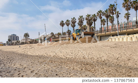 Beach restoration works in Barcelona with excavator and dump truck repairing sand on Mediterranean urban beach 137867563