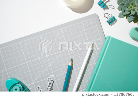 Mint color notebook, pencil, highlighters, and a glue on grey cutting mat. Copyspace Mint color notebook, pencil, highlighters, and a glue on grey cutting mat. Copyspace 137867603