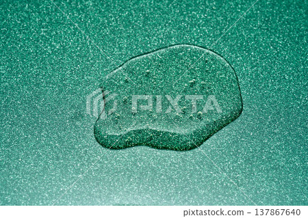 Liquid droplet on sparkling green surface creating texture Liquid droplet on sparkling green surface creating texture 137867640
